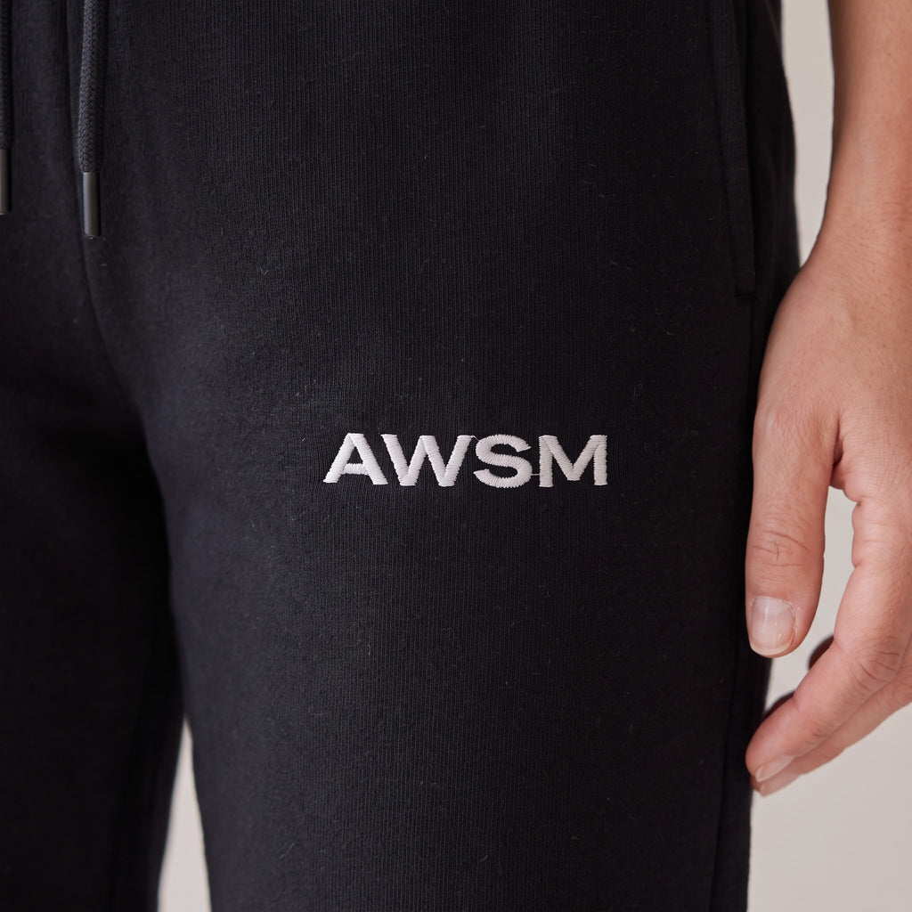 Basecamp Heavyweight Sweatpants — AWSM Field in Onyx Black, close-up of the embroidery on the AWSM house model