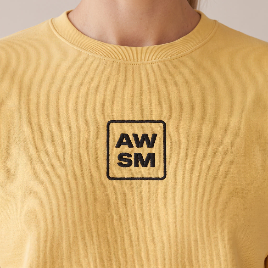 Brioche Crewneck — AWSM Atelier in Butter Cream, close-up of the embroidery on the AWSM house model