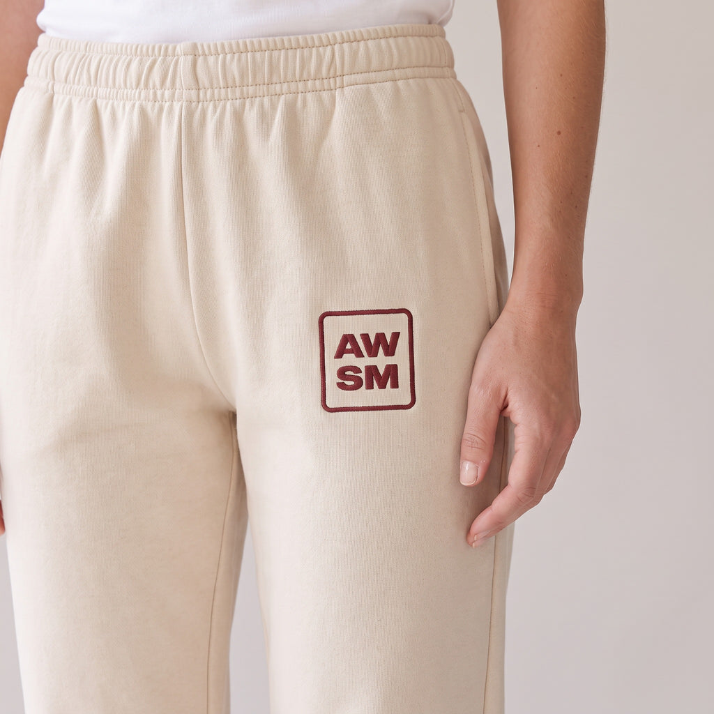 Cabernet Heavyweight Sweatpants — AWSM Atelier in Stone Dust, close-up of the embroidery on the AWSM house model