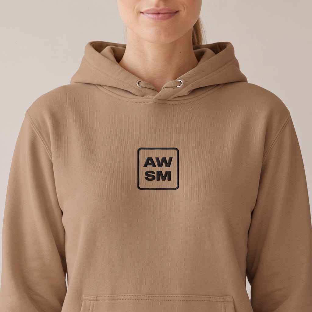 Galerie Hoodie — AWSM Atelier in Café Latte, close-up of the embroidery on the AWSM house model
