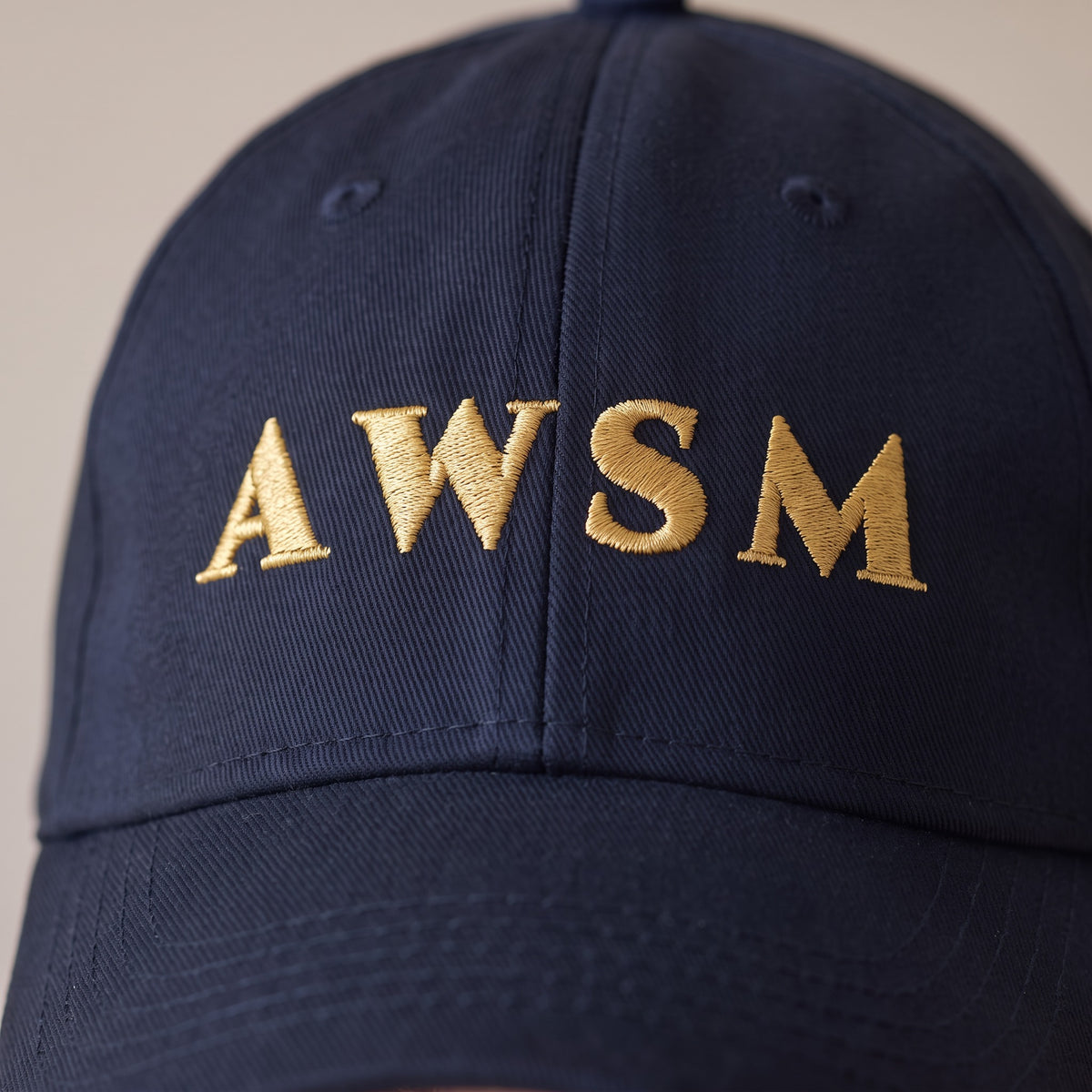 Laurel Dad Hat — AWSM Aurum in Midnight Navy, close-up of the embroidery on the AWSM house model