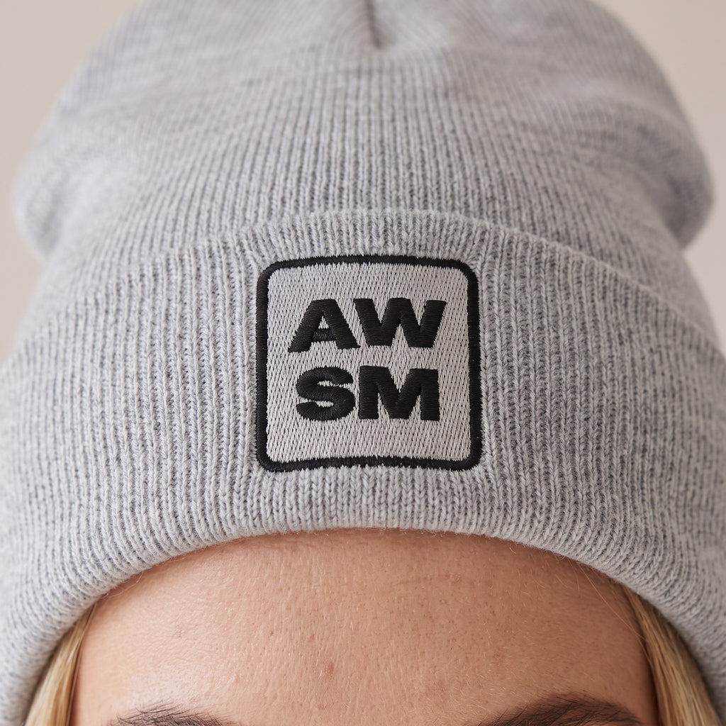 Neige Cuffed Beanie — AWSM Atelier in Cloud Heather Grey, close-up of the embroidery on the AWSM house model
