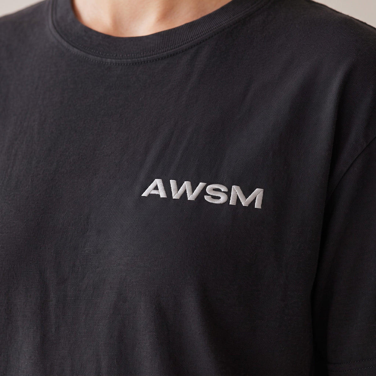 Outpost Heavyweight Tee — AWSM Field in Onyx Black, close-up of the embroidery on the AWSM house model