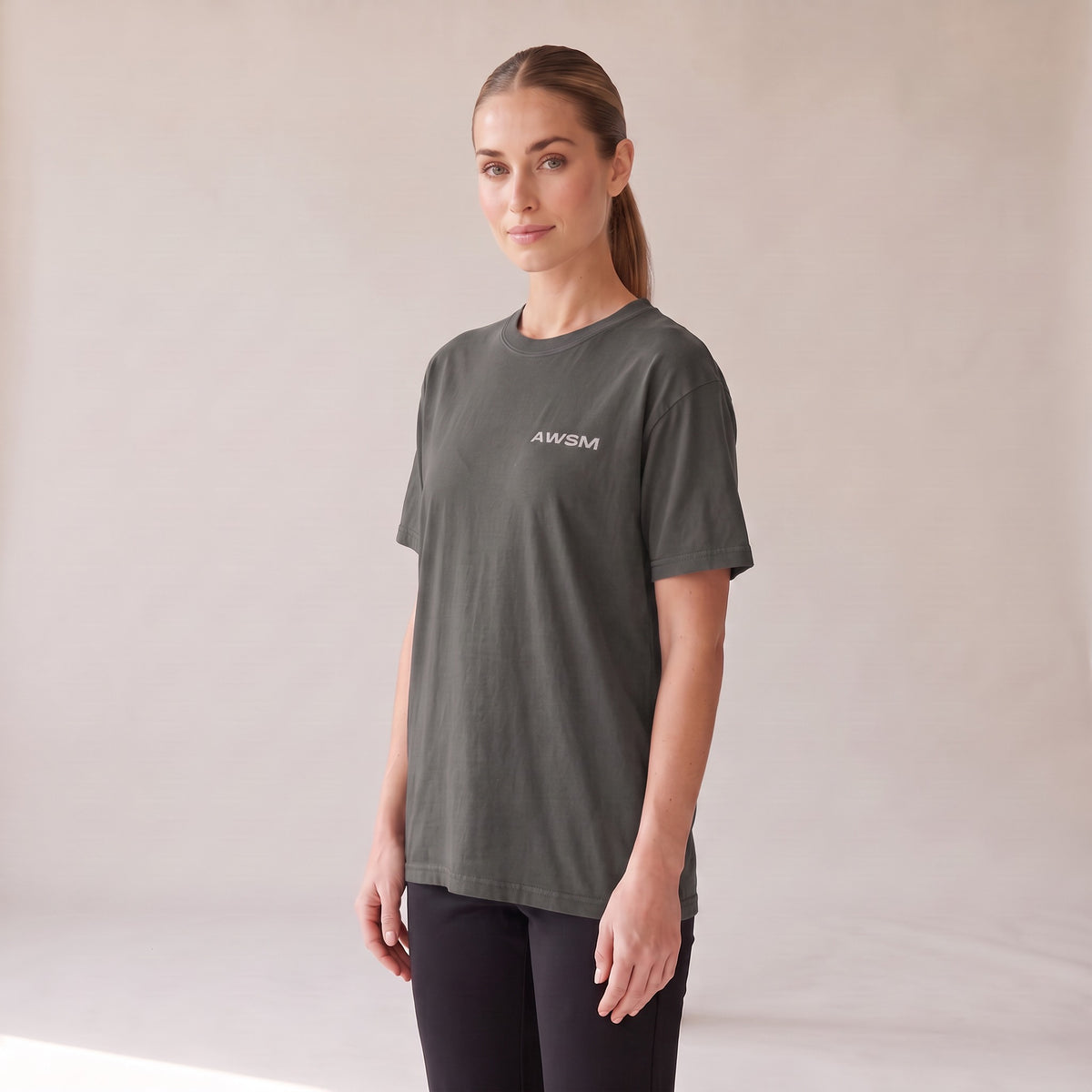 Outpost Heavyweight Tee — AWSM Field in Peppercorn Grey, three-quarter view on the AWSM house model