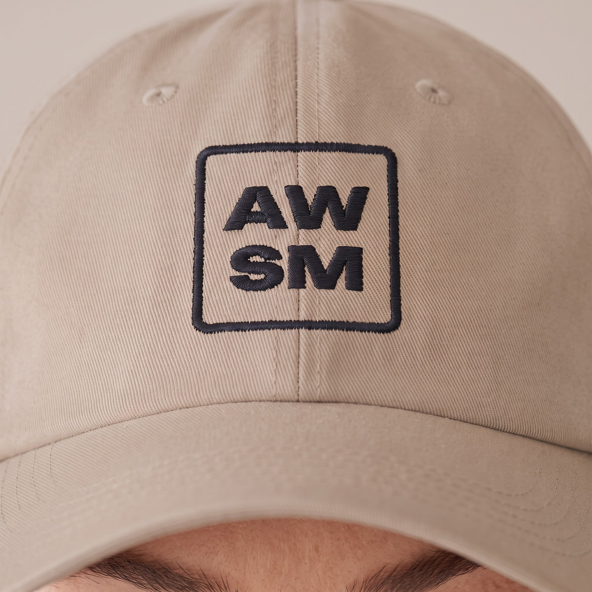 Plâtre Dad Hat — AWSM Atelier in Limestone, close-up of the embroidery on the AWSM house model