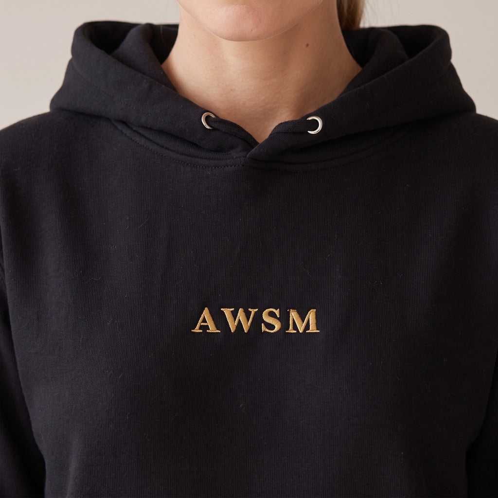 Regalia Hoodie — AWSM Aurum in Onyx Black, close-up of the embroidery on the AWSM house model