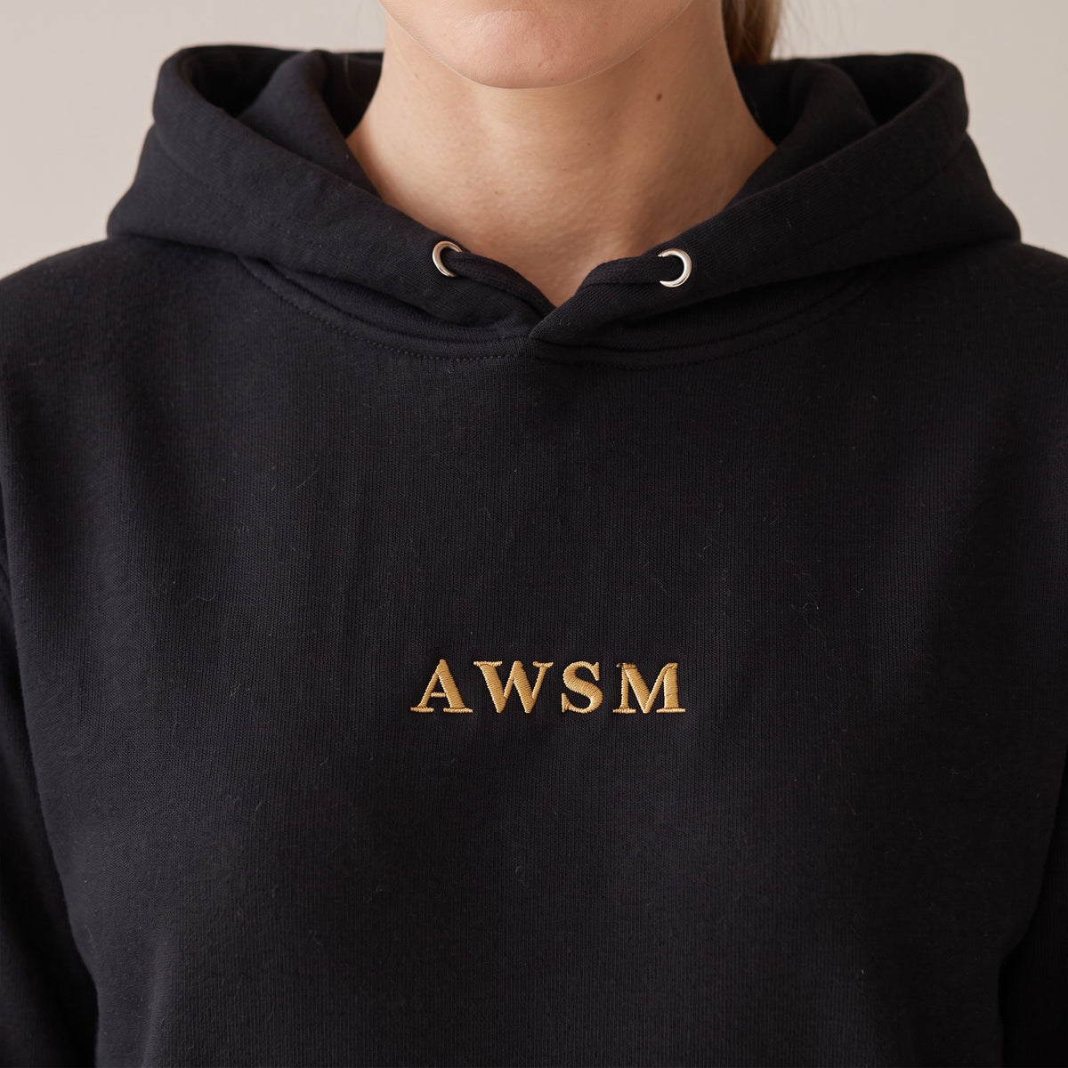 Regalia Hoodie — AWSM Aurum in Onyx Black, close-up of the embroidery on the AWSM house model