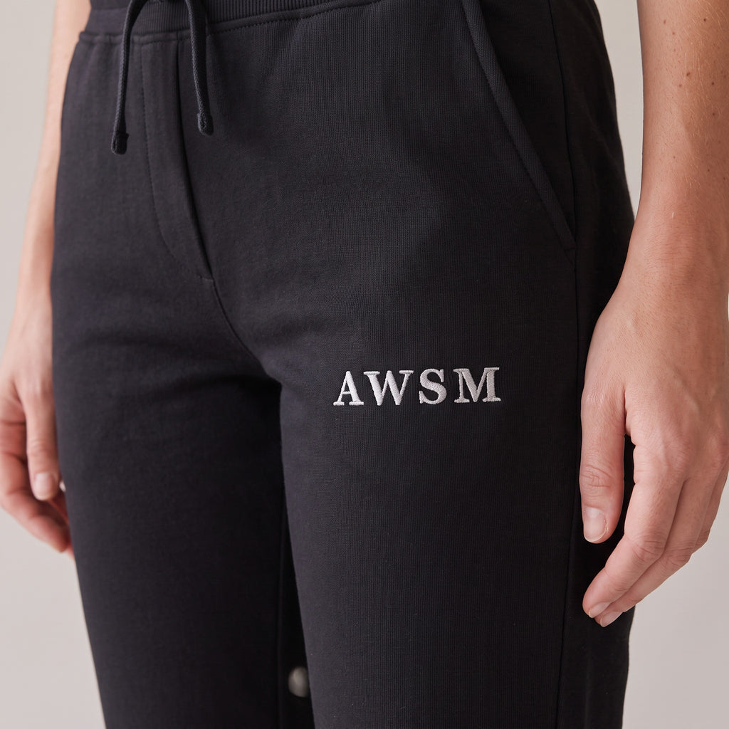 Repos Fleece Sweatpants — AWSM Maison in Onyx Black, close-up of the embroidery on the AWSM house model