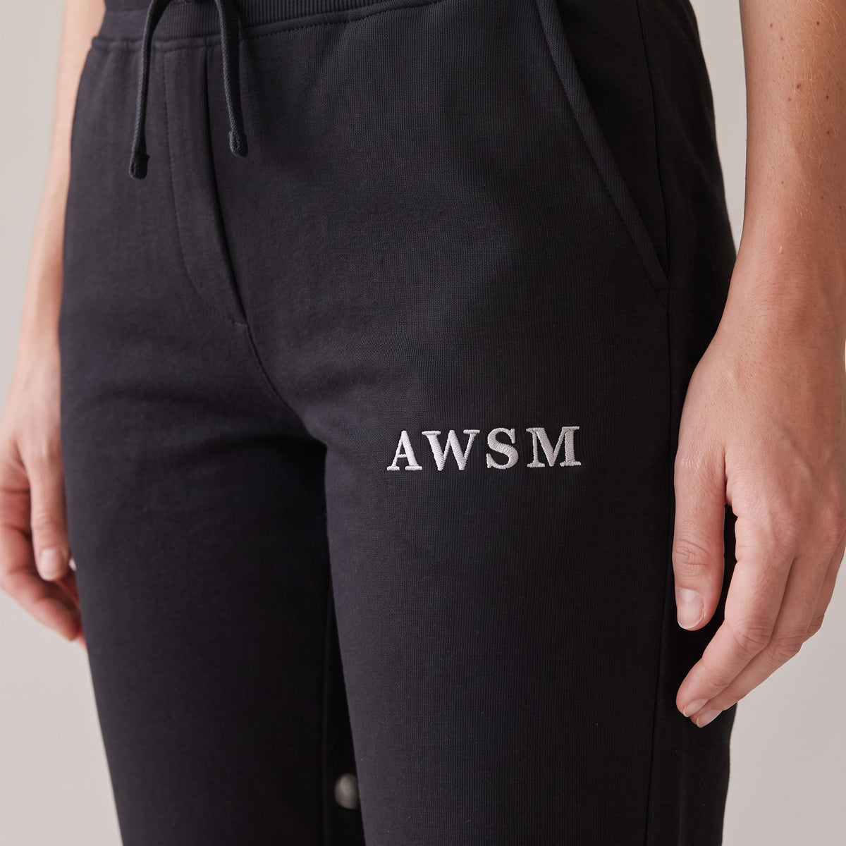 Repos Fleece Sweatpants — AWSM Maison in Onyx Black, close-up of the embroidery on the AWSM house model