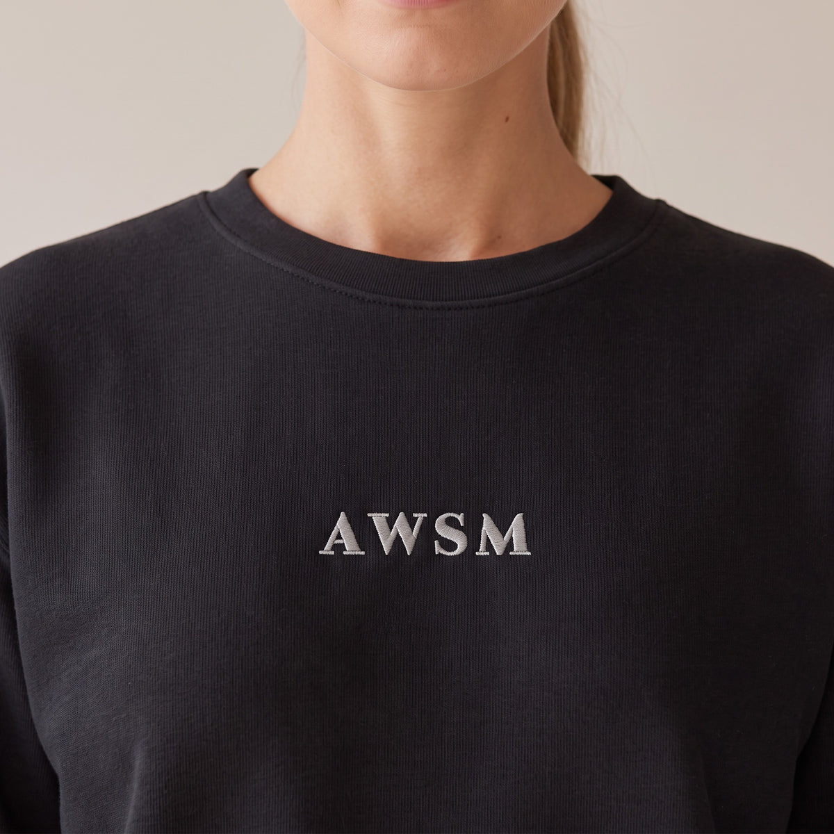 Salon Crewneck — AWSM Maison in Onyx Black, close-up of the embroidery on the AWSM house model