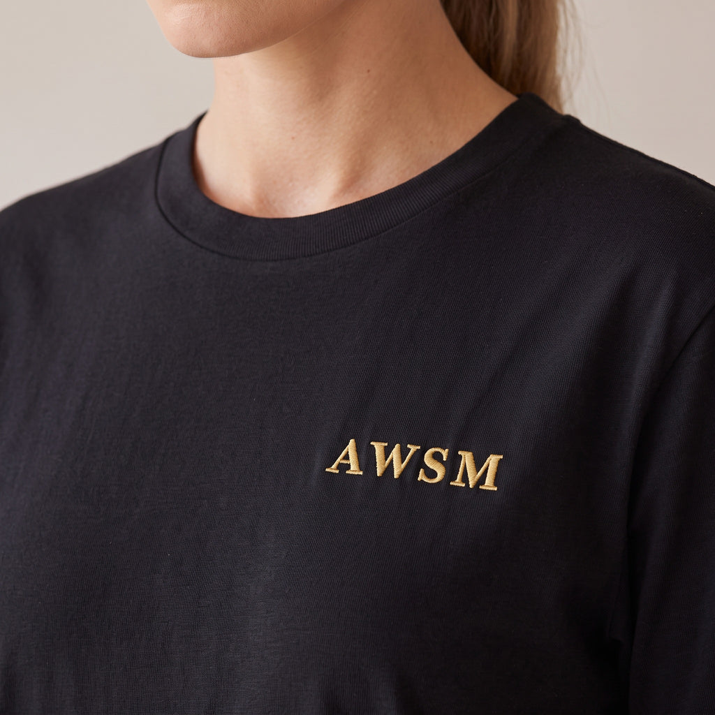 Sovereign Heavyweight Tee — AWSM Aurum in Onyx Black, close-up of the embroidery on the AWSM house model