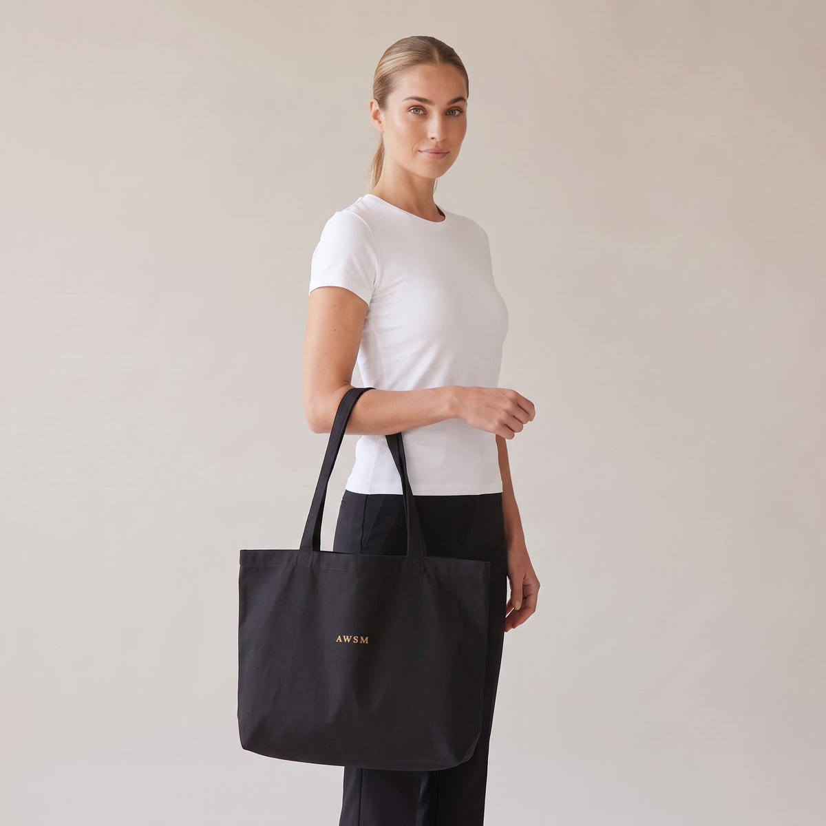 Trésor Twill Tote — AWSM Aurum in Onyx Black, three-quarter view on the AWSM house model
